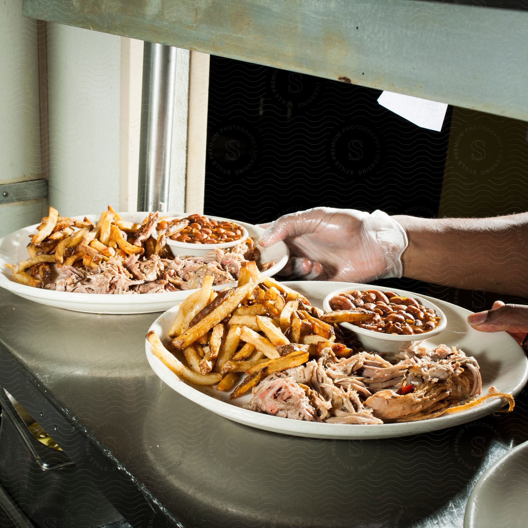 A cook places two plates of food on a counter in a restaurant kitchen