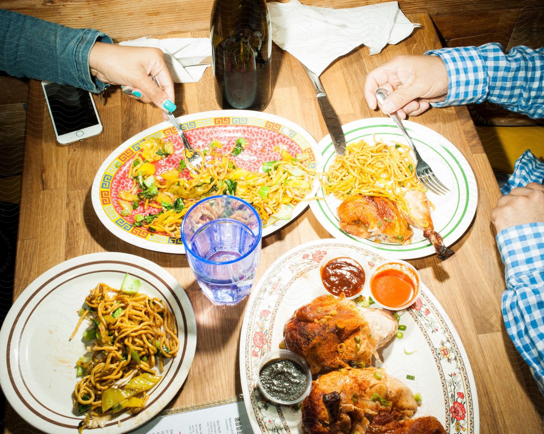 Two people eating noodles and chicken at a restaurant