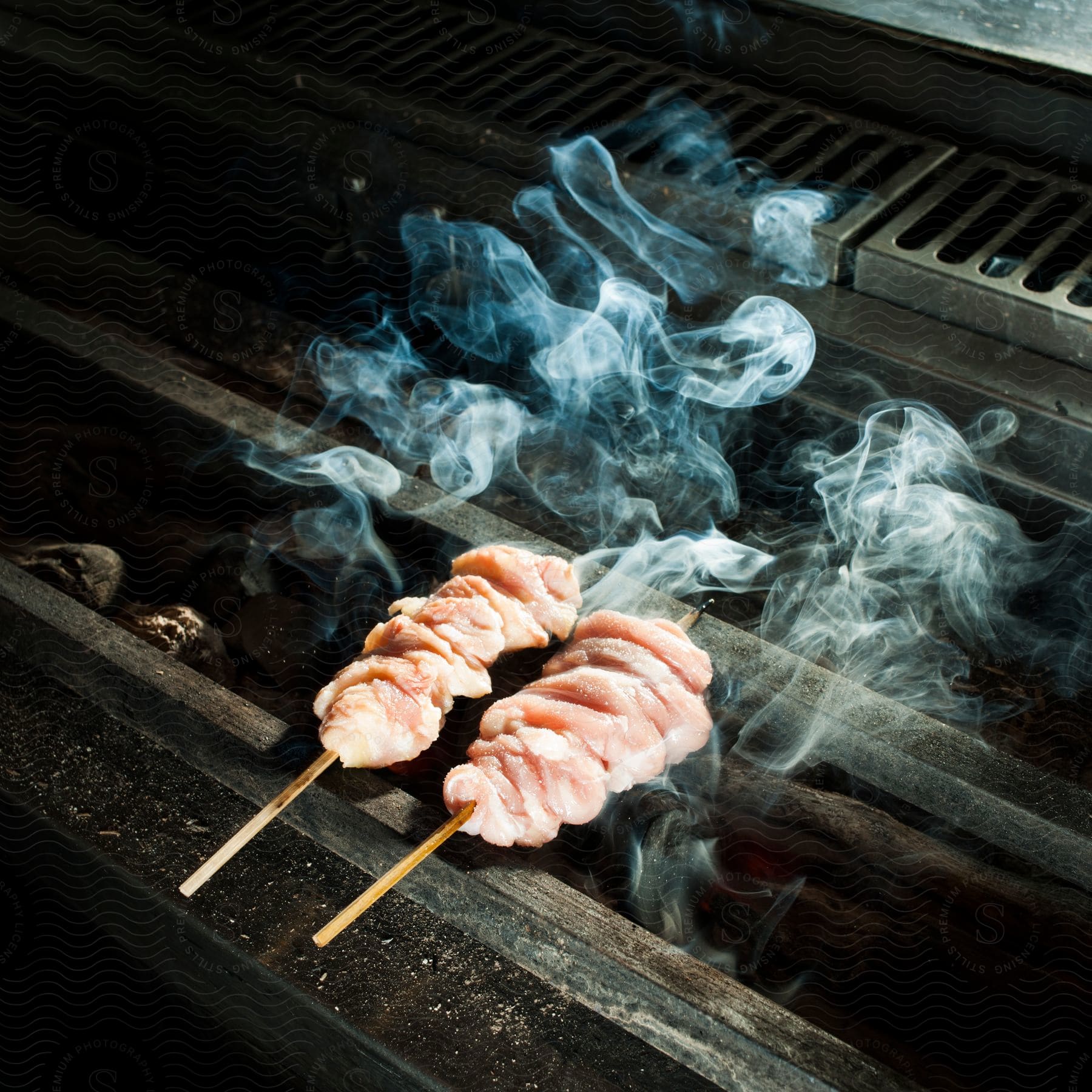 Skewered chicken cooking and smoking on a large grill