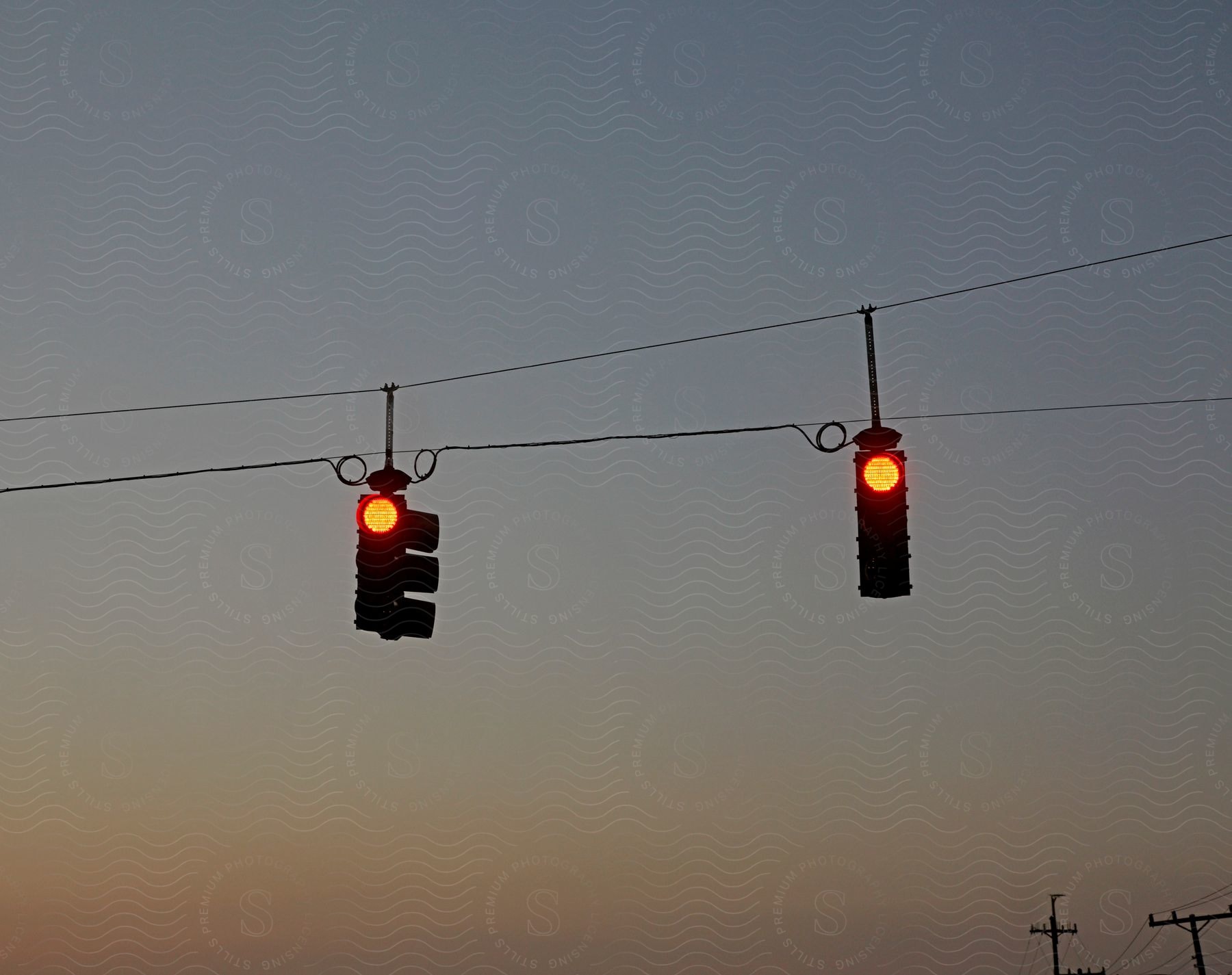 Traffic lights hang on cables under the twilight sky
