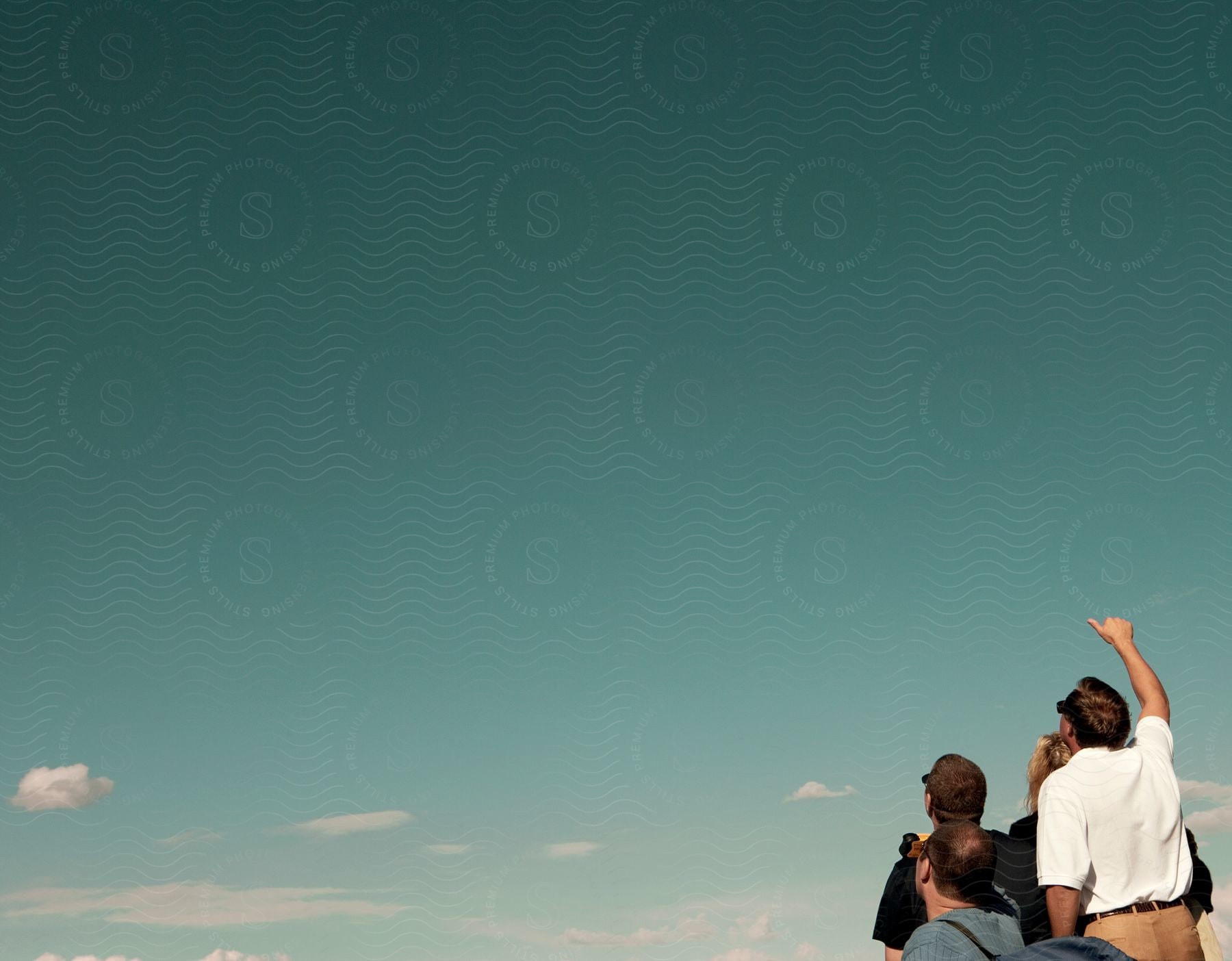 Group of friends looking up at the sunny sky with a few clouds