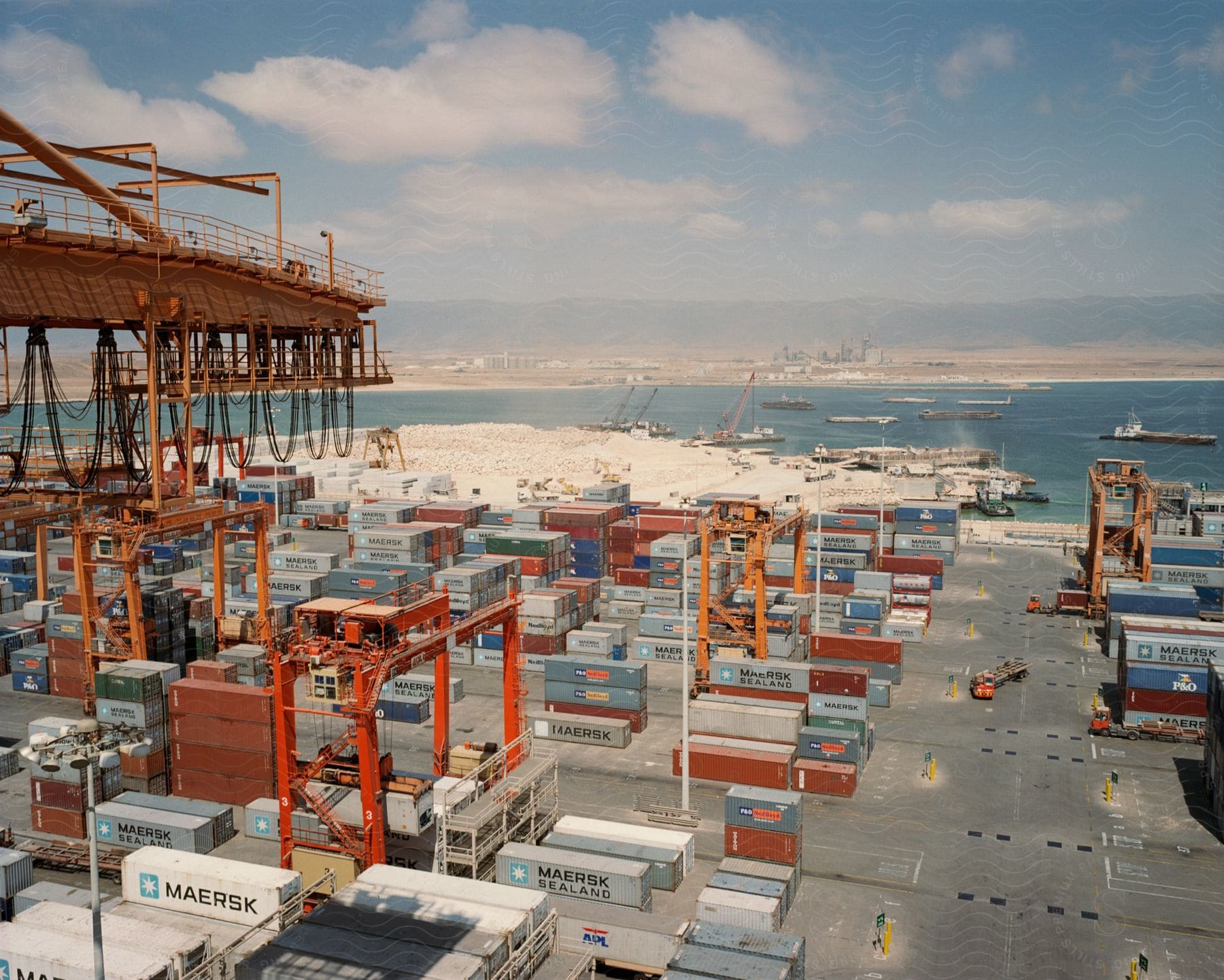 Cargo containers line a shipping yard along the coast