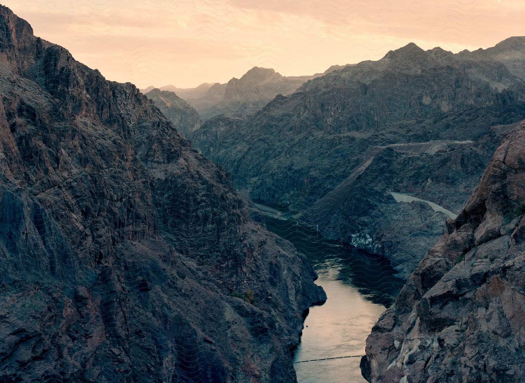 A calm stream flows through a canyon between mountains