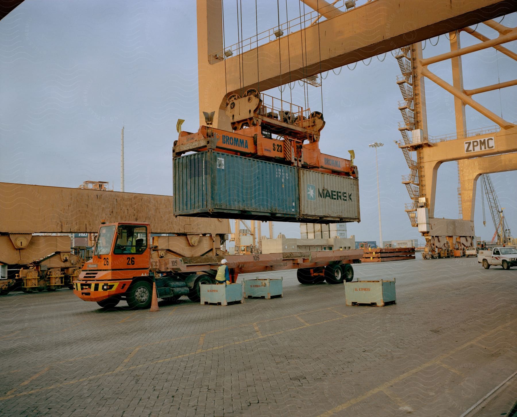 Two shipping containers being loaded onto a truck bed at the shipping yard