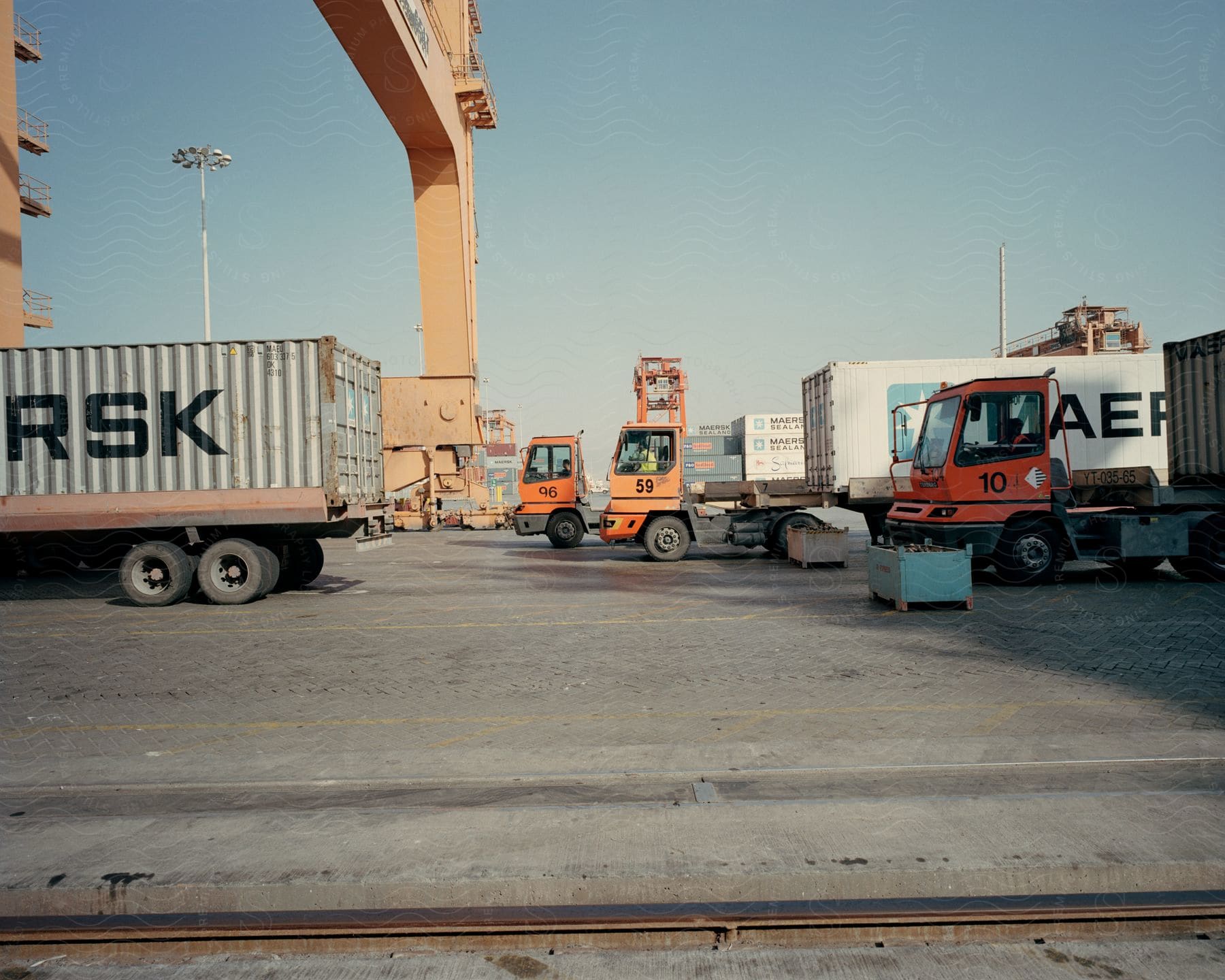 Three cargo truck drivers wait impatiently on a shipping dock to offload their cargo containers