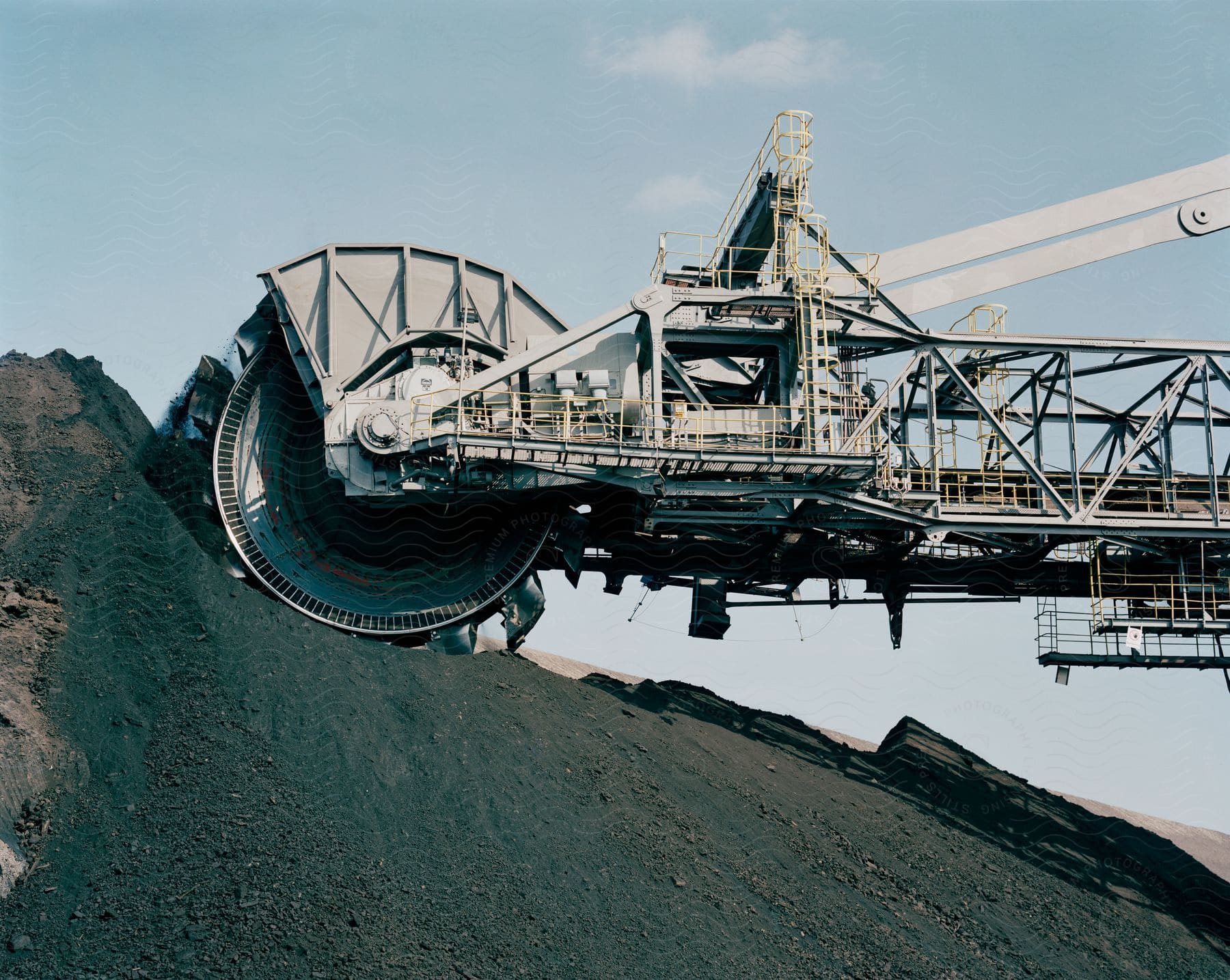 A machine with a rotating blade digging into a rocky hill in a gravel pit
