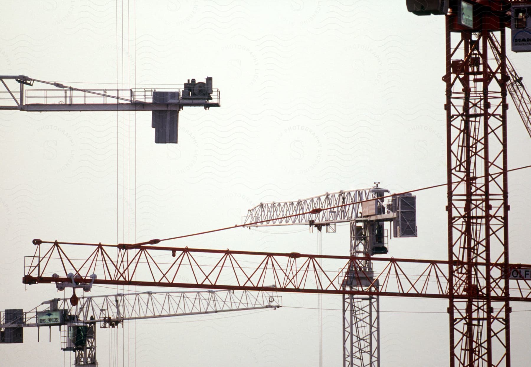 Multiple ship loading cranes hover in the air under a pale sky