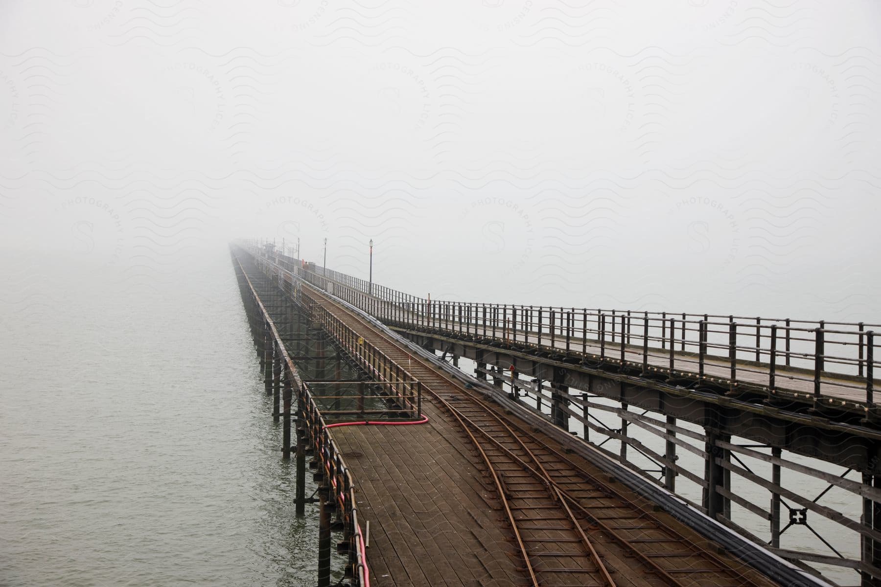 A bridge with a track on it suspended over the ocean on a hazy day