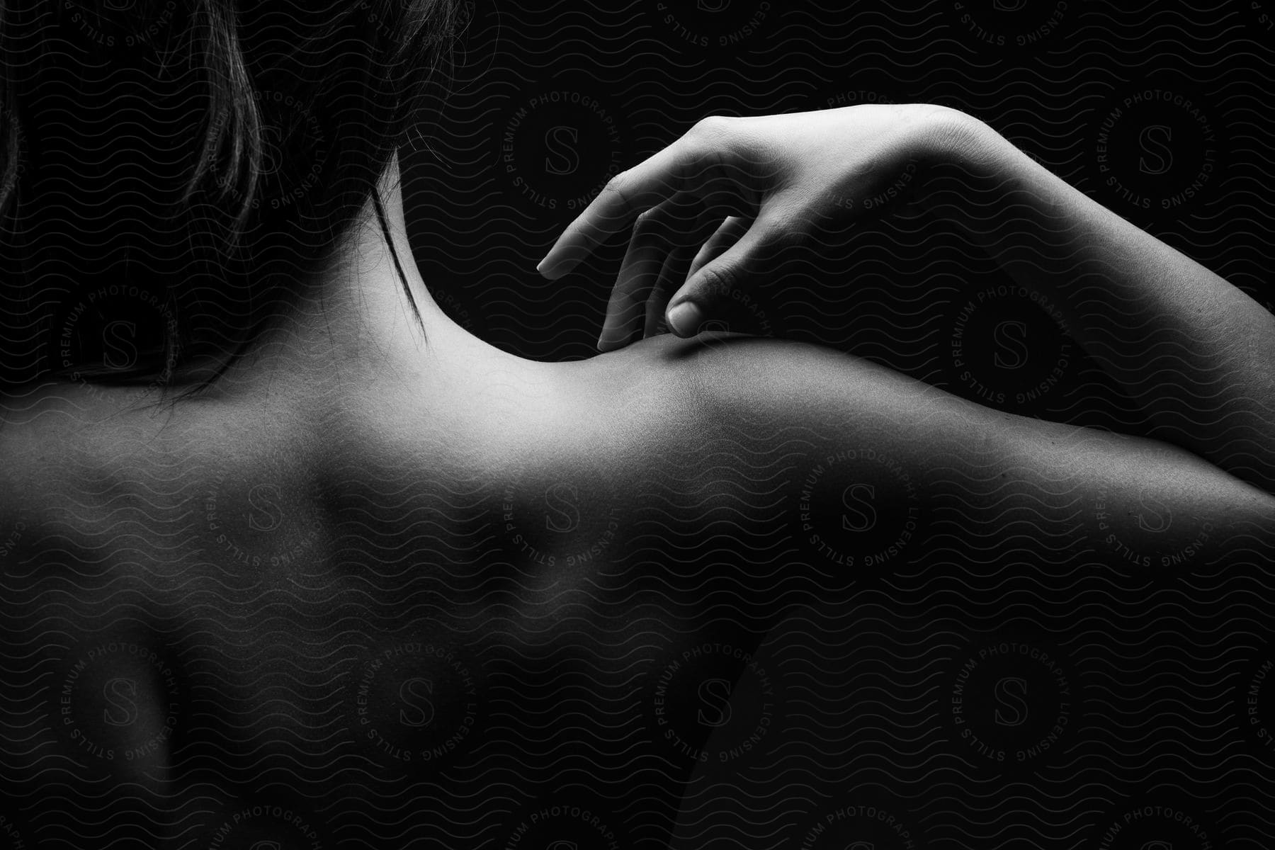 A womans shoulders hand and arm are visible in a dark room