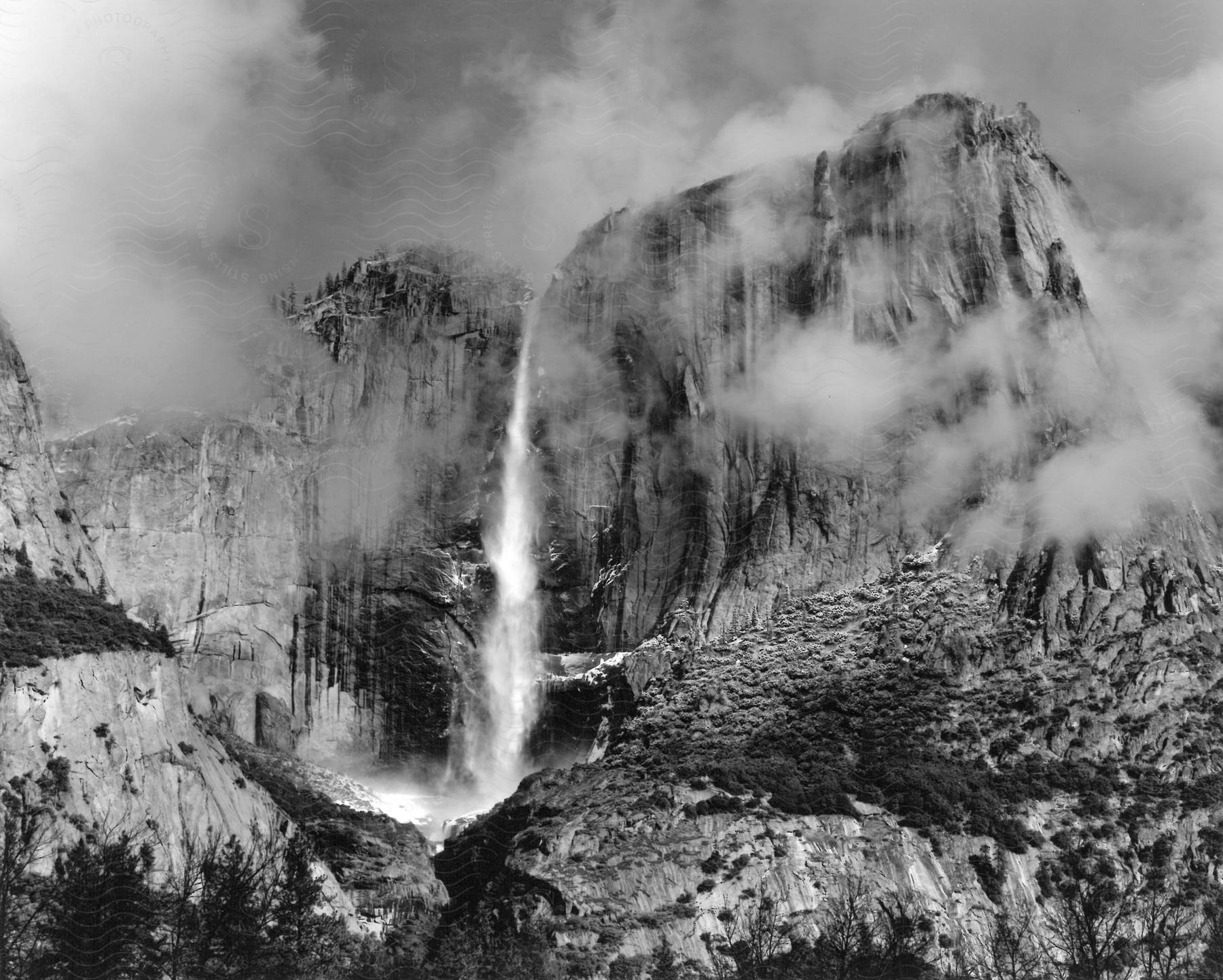 Canyons with billowy clouds or fog and a waterfall in black and white