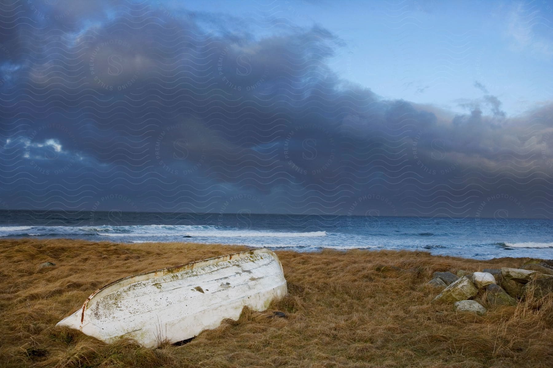 An Overturned Canoe On A Sandy Beach With A Dark Cloud In The Sky