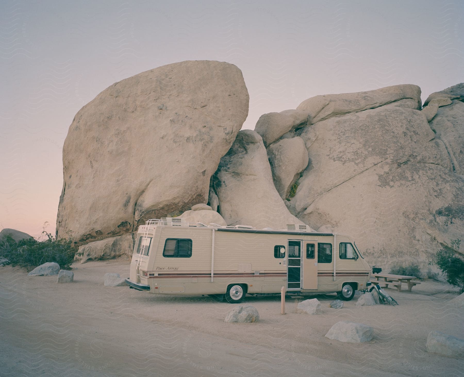 A motorhome parked near a large rock in a natural outdoor setting