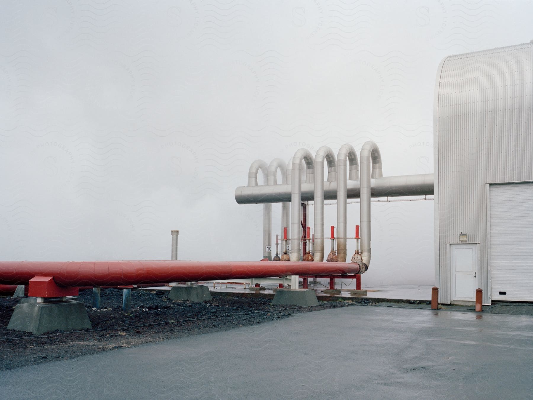 A pipeline in an outdoor setting with water sky and asphalt