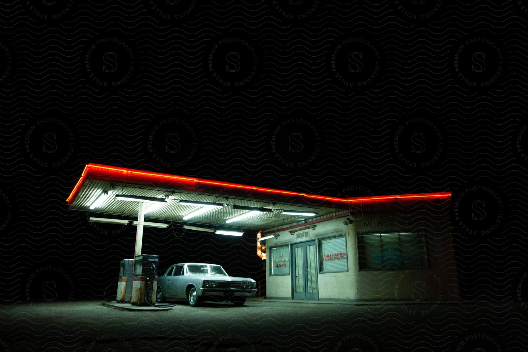 Gas station at night with one blue car parked at the gas pump under the lights