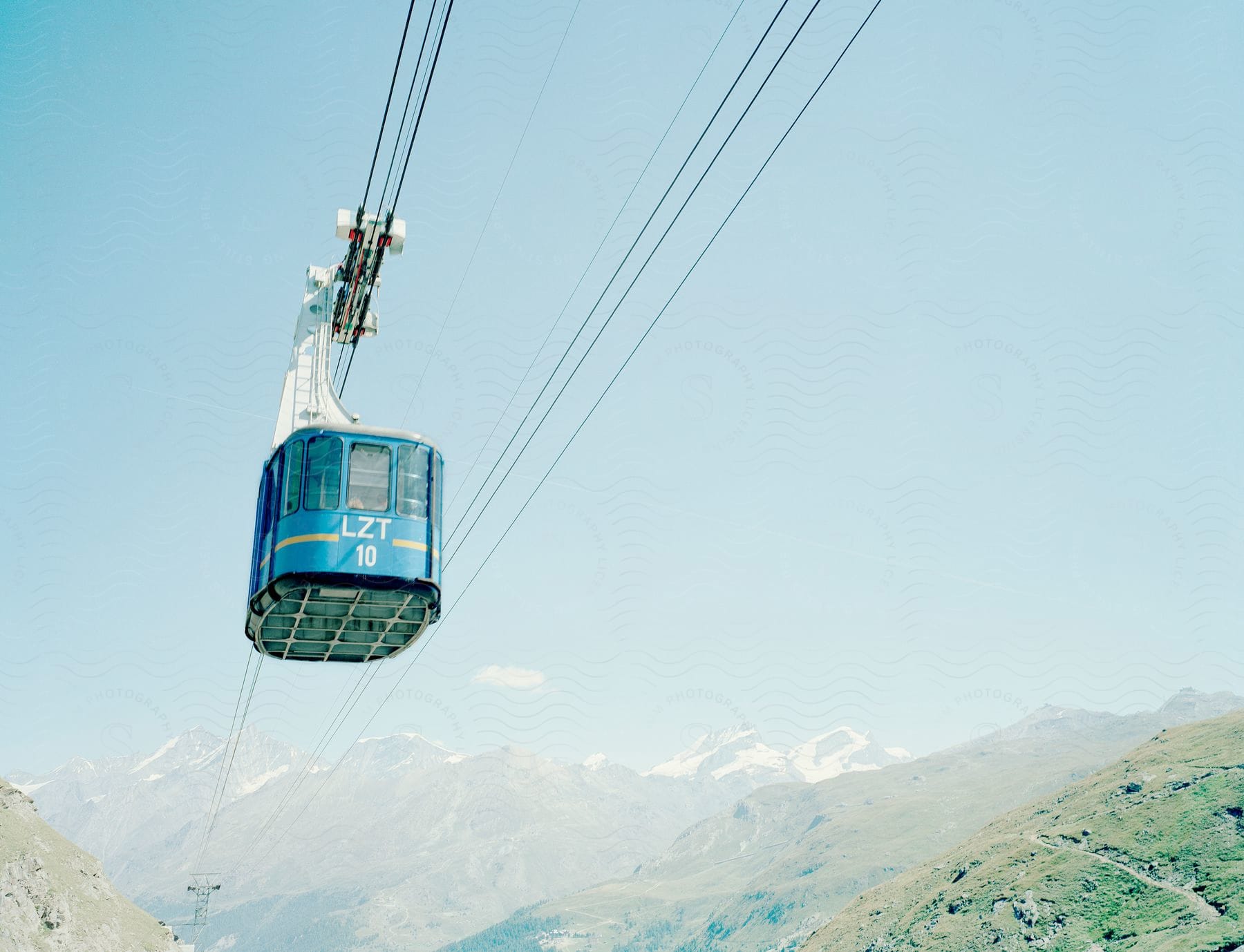 A cable car with mountains in the background on a sunny day