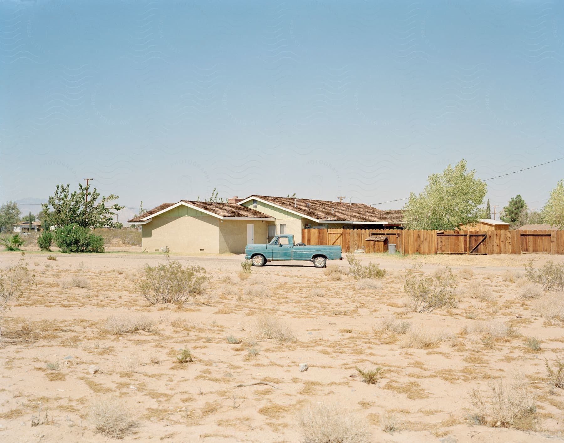 A wide land with an old small building and a blue truck parked on the land