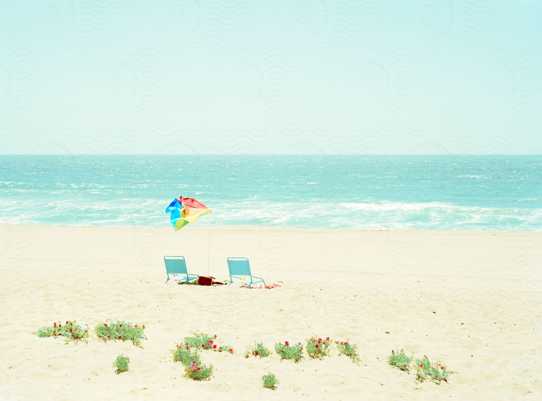 A beach near the ocean with two chairs and an umbrella