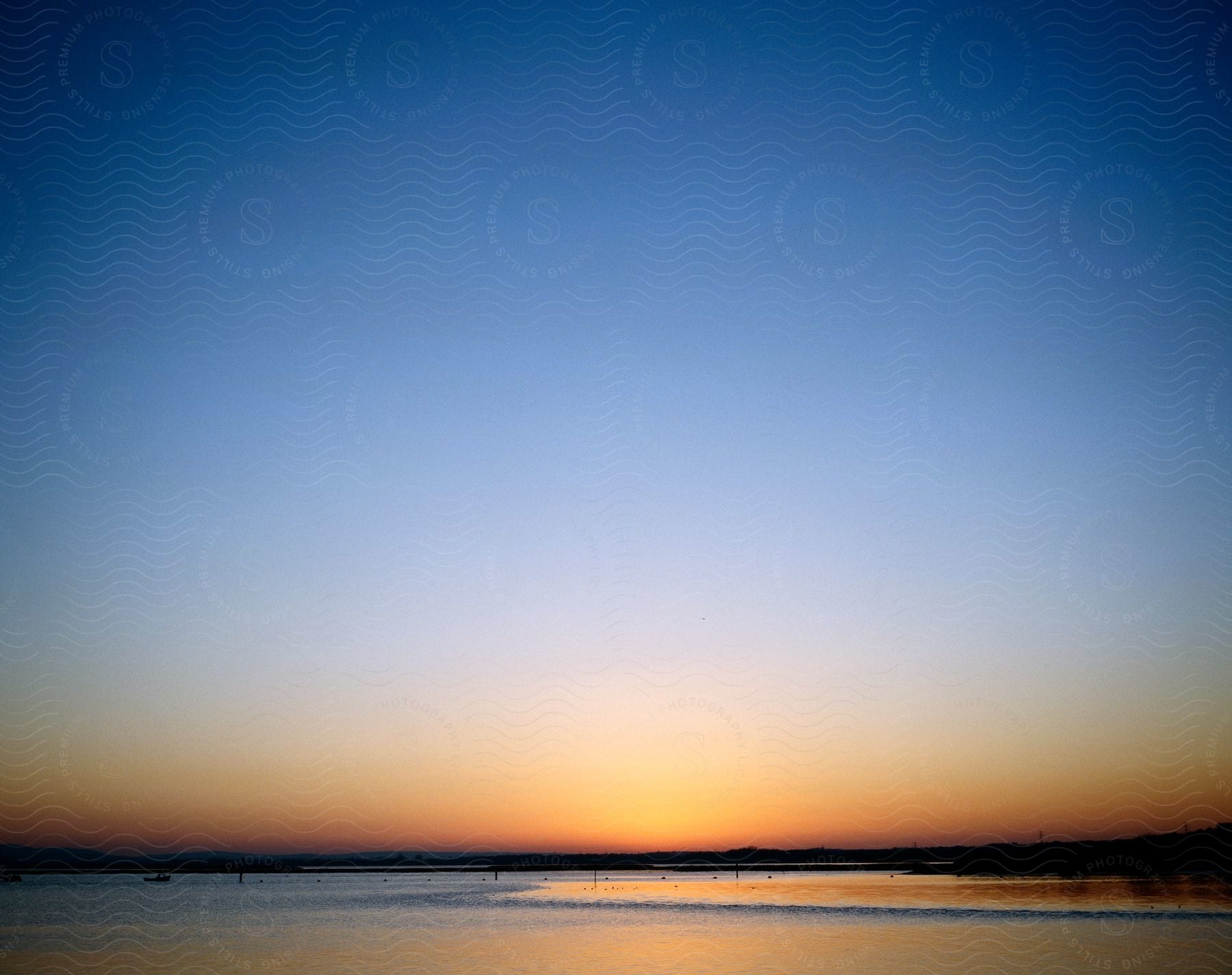 A natural landscape of a beach at dusk with colorful orange sky and water reflection