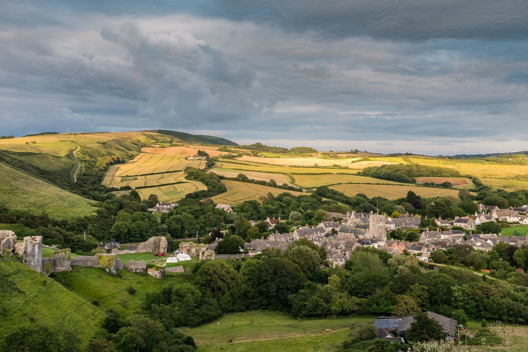 A country town with a ruined castle and stone church next to cultivated fields