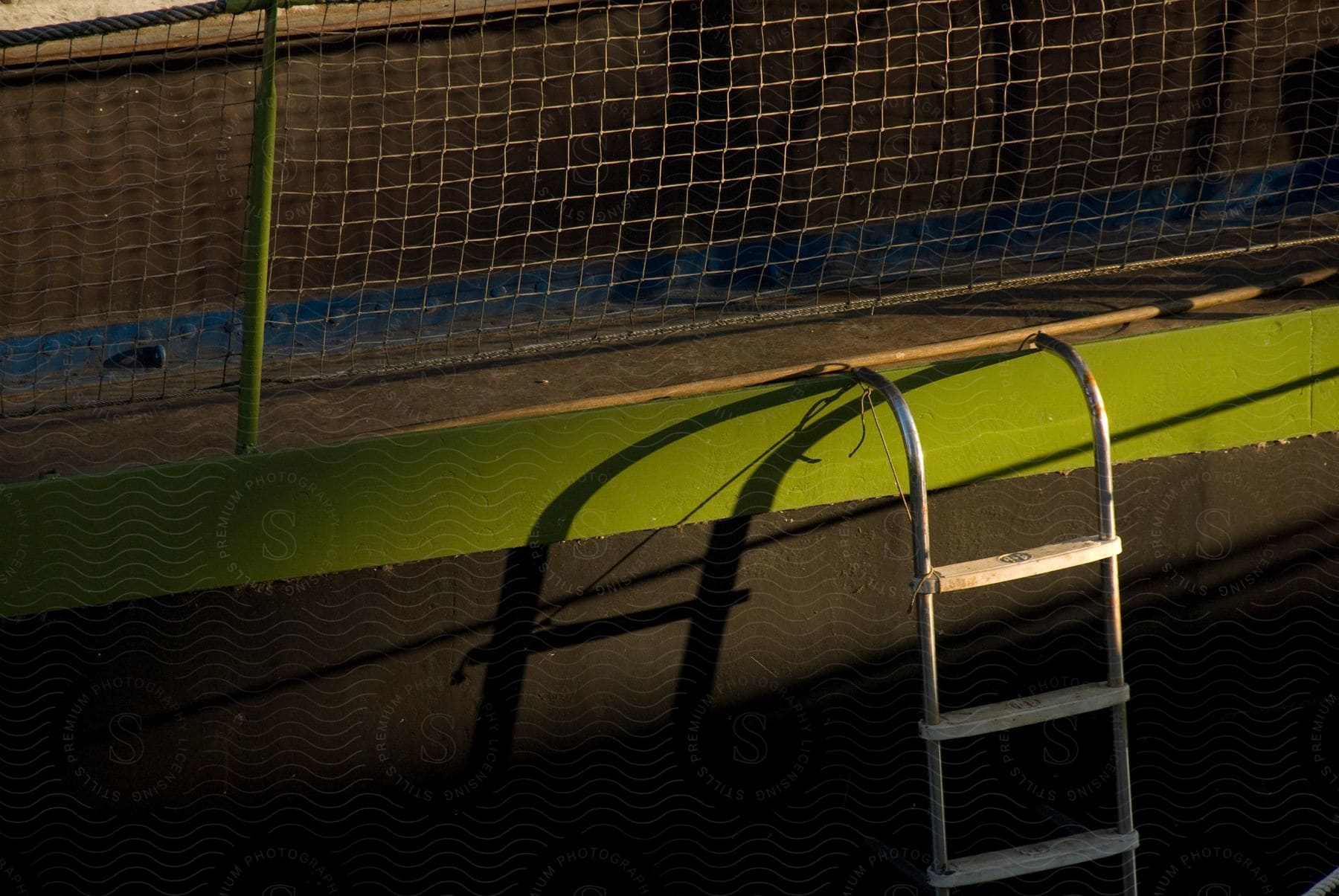 A ladder hangs off the side of an emptied swimming pool