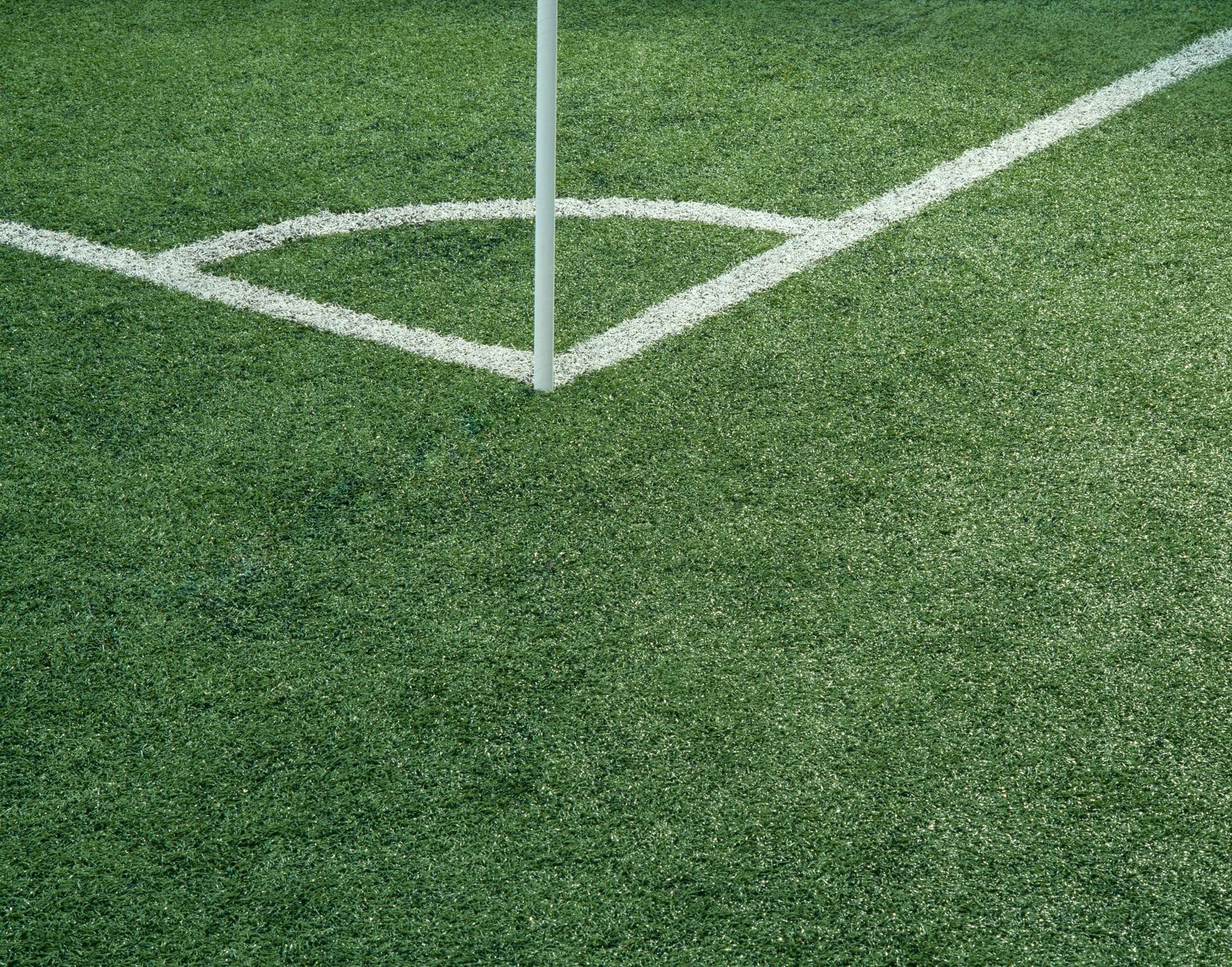 A corner of a soccer field with green grass and white lines