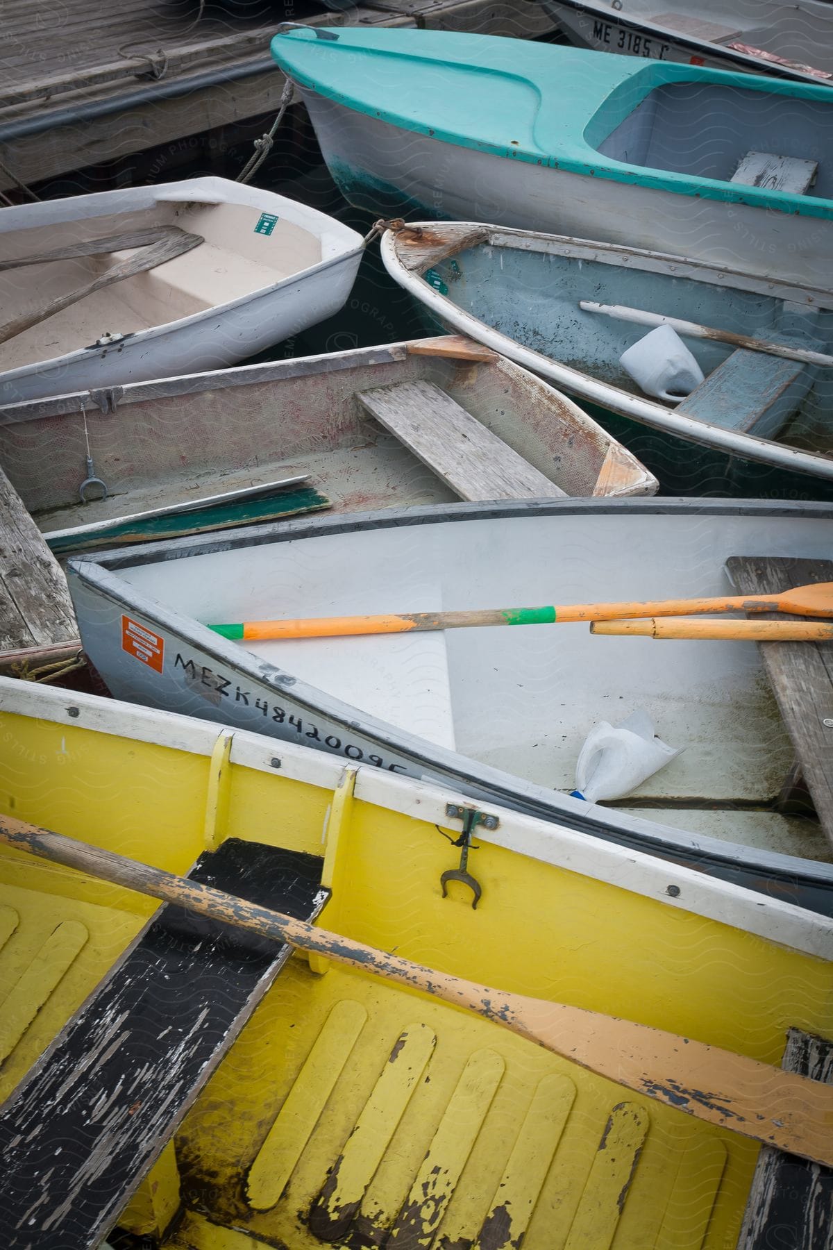 Several colorful boats lined up side by side with paddles on top of them