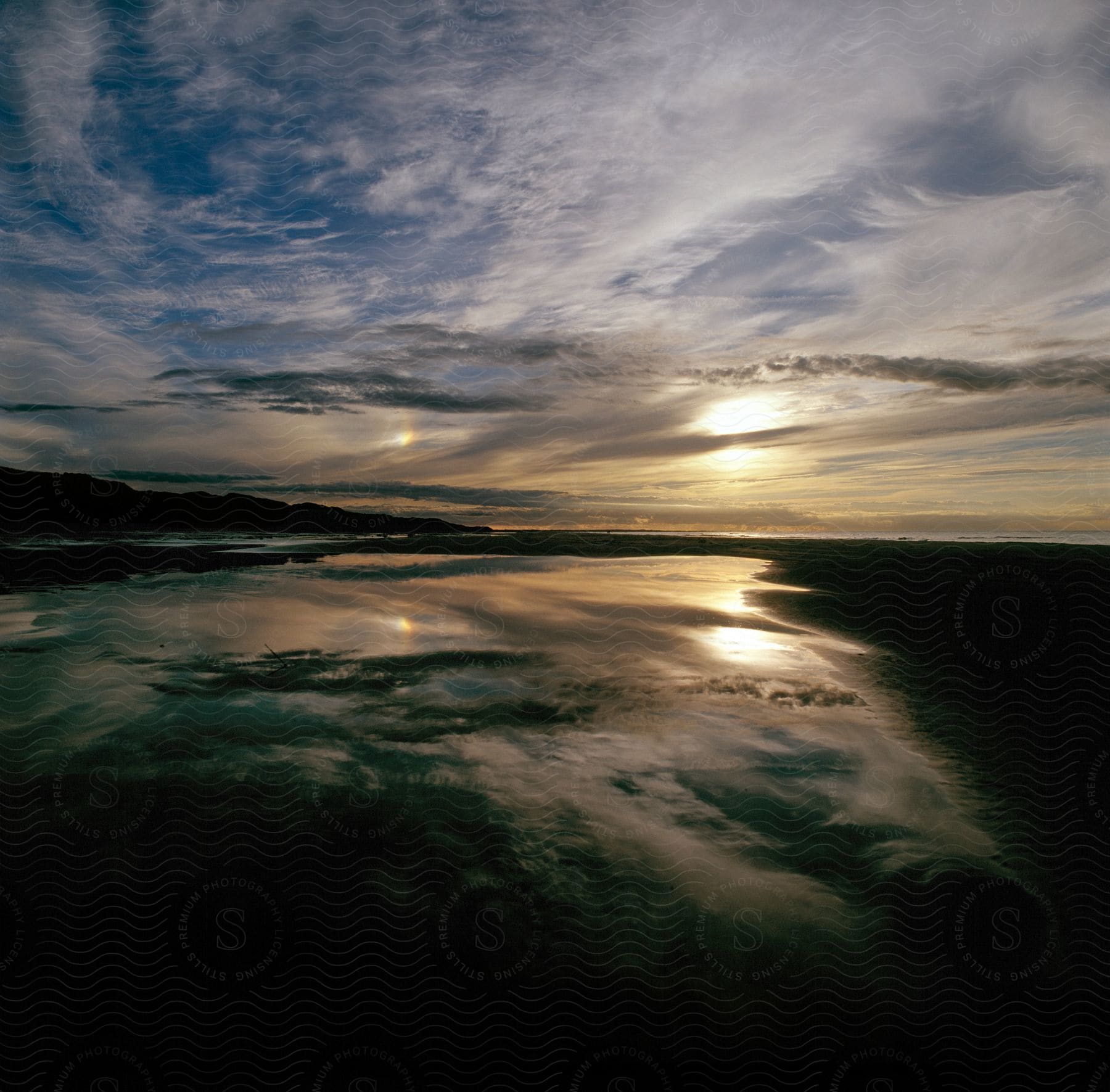 The sun is setting on the horizon of the ocean and coast