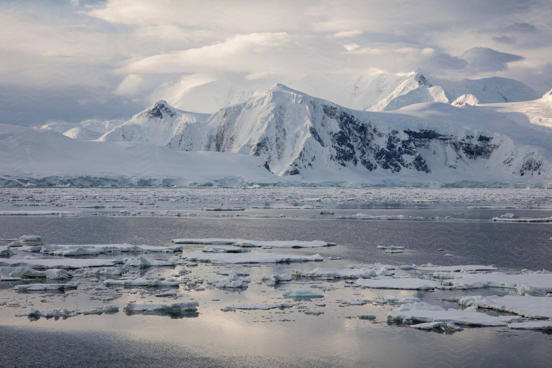 An arctic landscape photographed during midday with mountains ice and a body of water