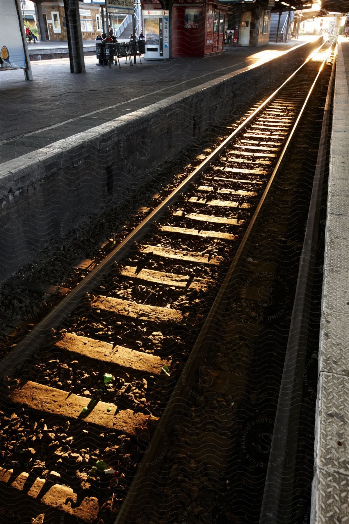 Sunlight shines over train tracks in a train station at evening