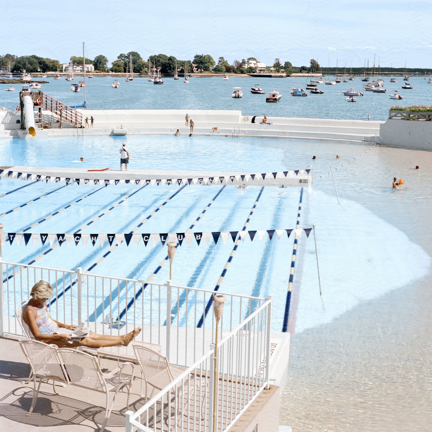 People enjoying themselves at a waterfront yacht club pool during summer