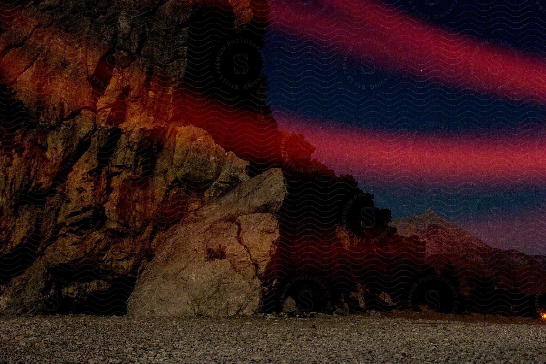 A rocky cliff with red lights illuminating it