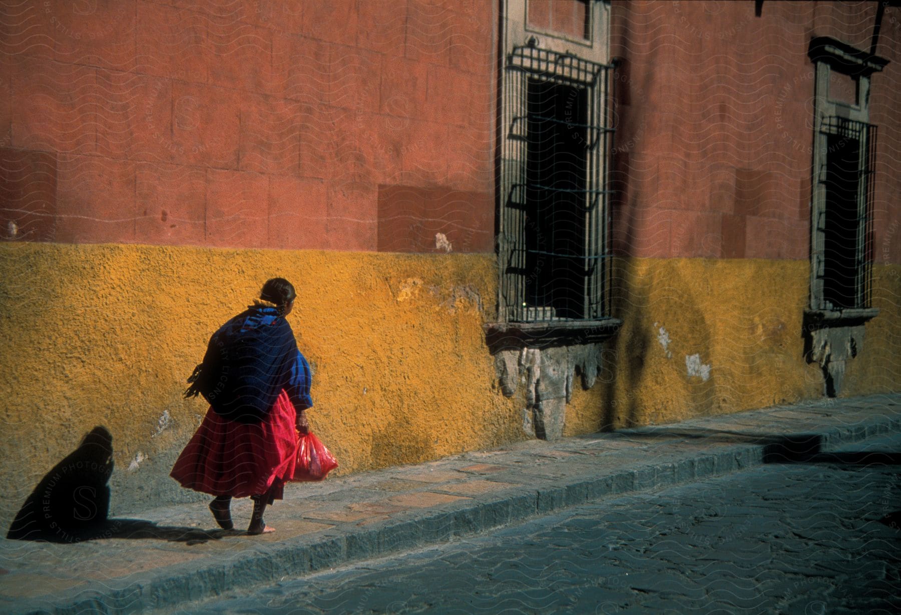 A woman carries a bag on the sidewalk by an old building