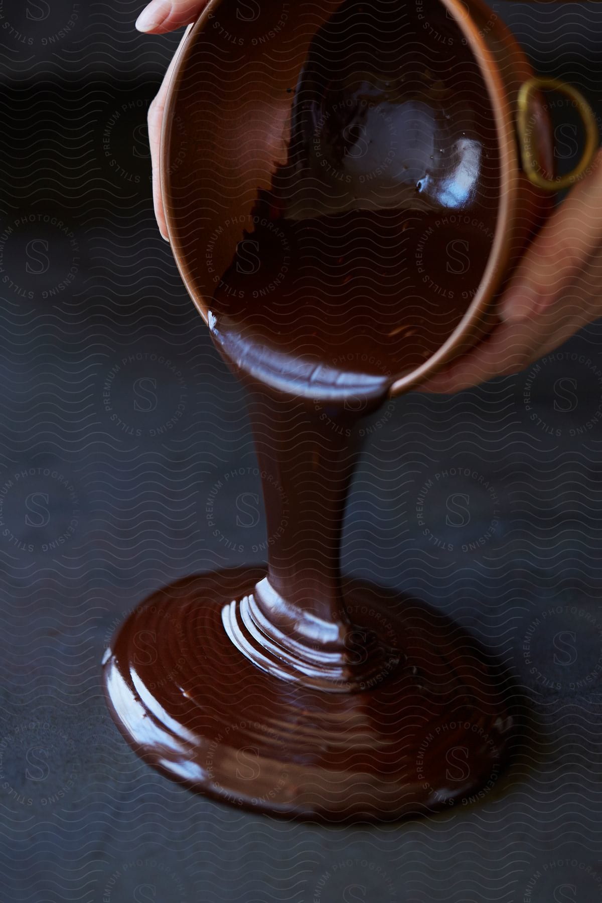 Chocolate syrup pours from a bowl