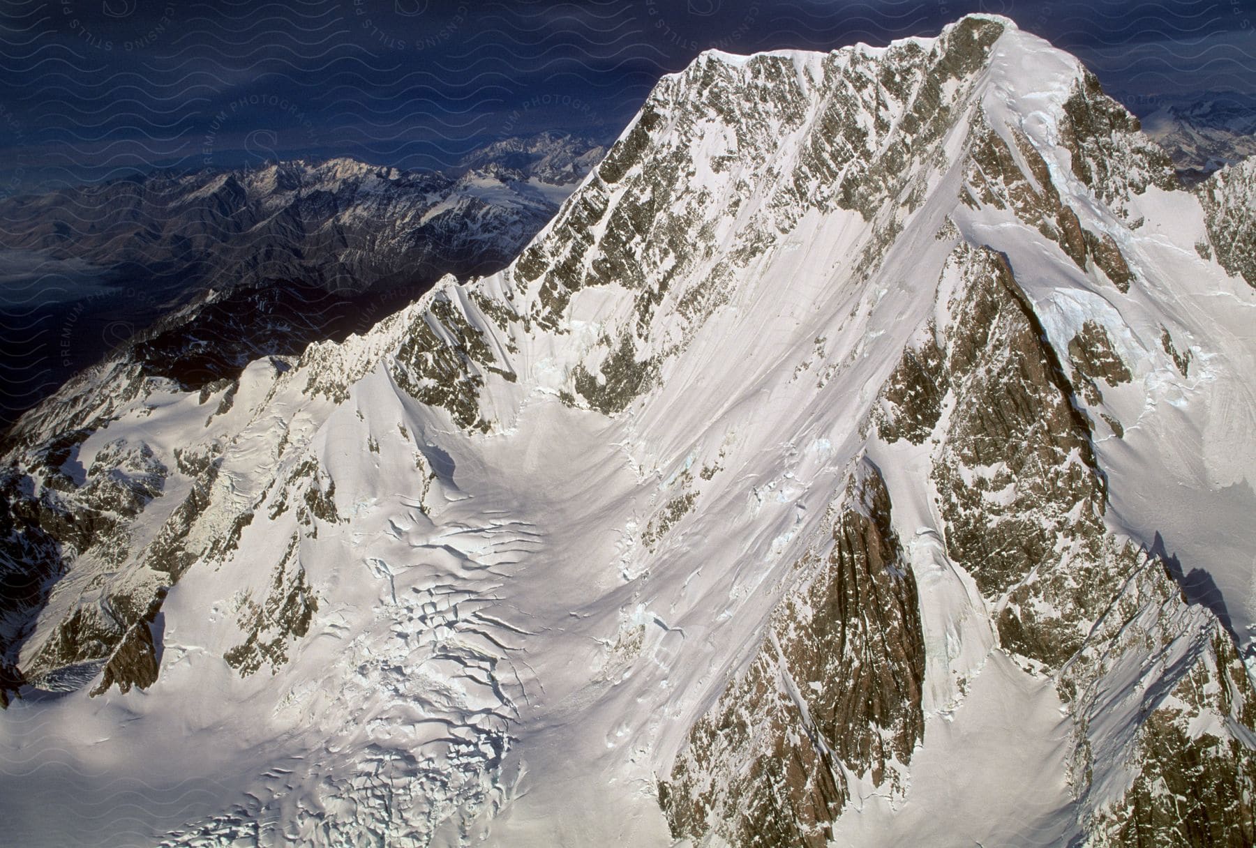 Snowcovered mountain peak in daylight surrounded by a mountain range