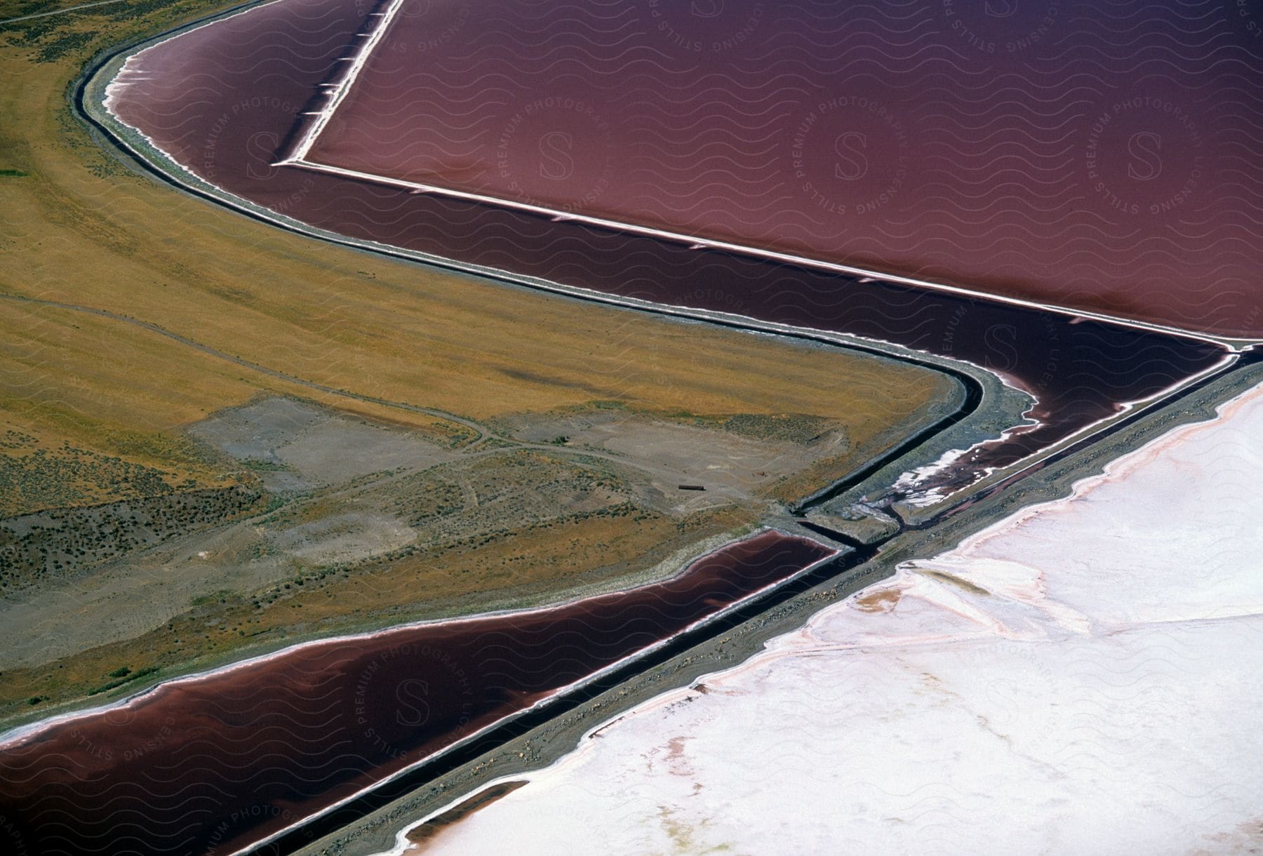 Stock photo of a road runs parallel and crosses a purple channel between scrub land and white and purple terrain