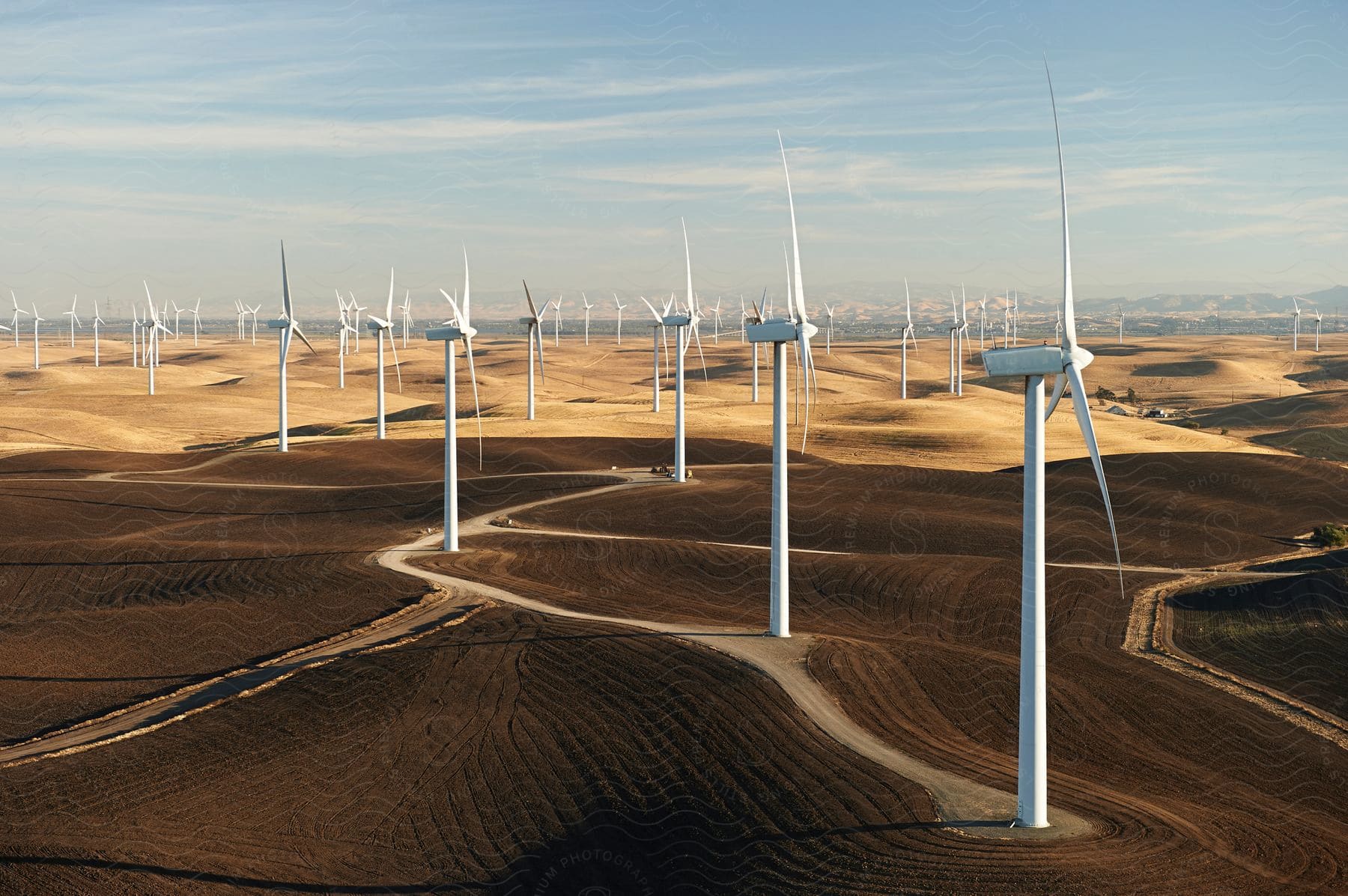 The sun shines upon turbines on a wind farm in the desert