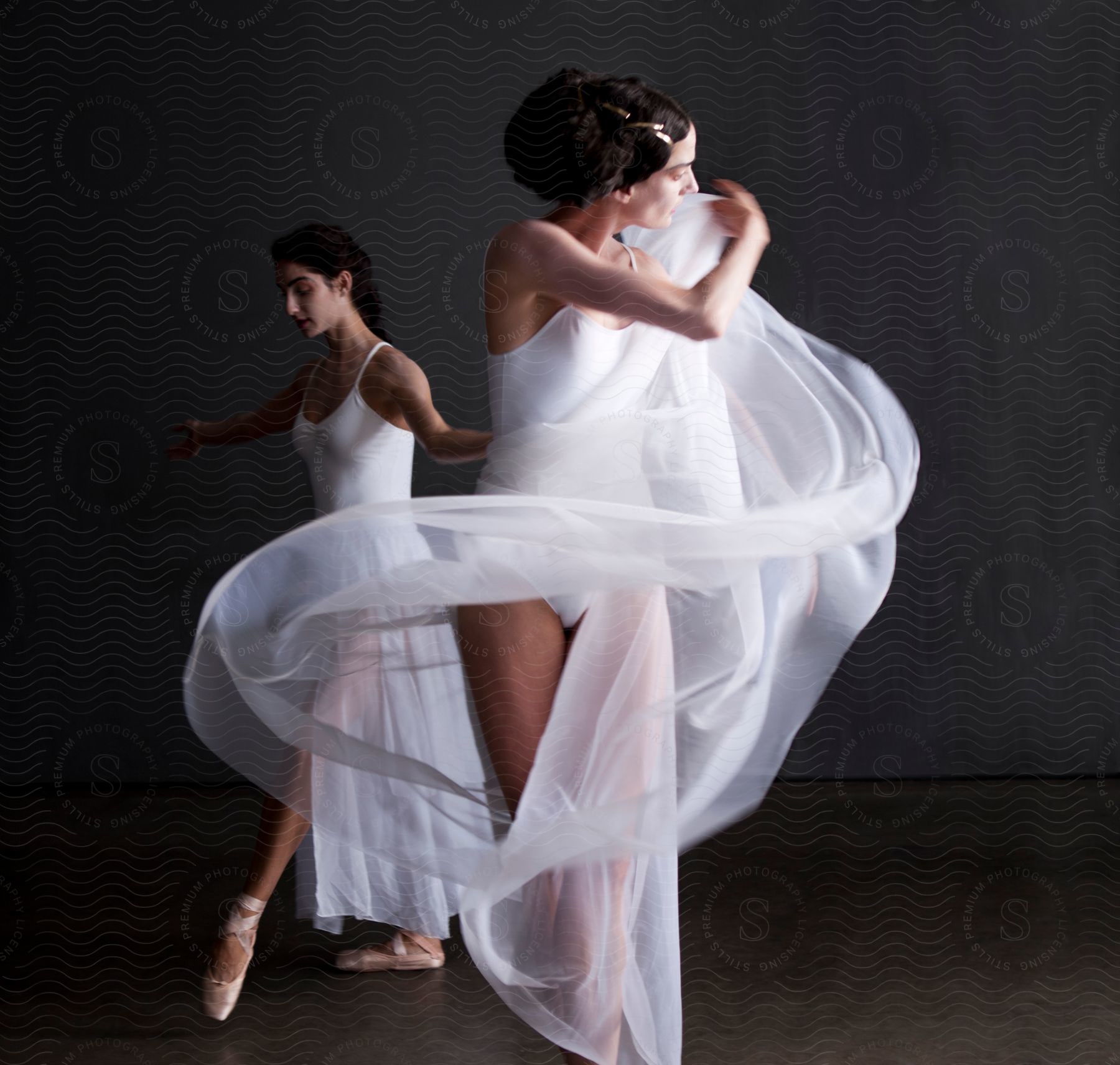 Two ballerinas dancing one holding a sheer white veil