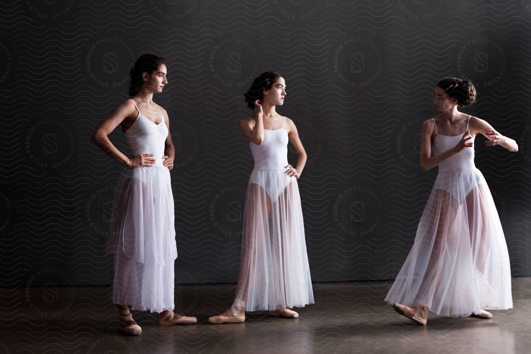 Three women in ballet attire are engaged in a conversation