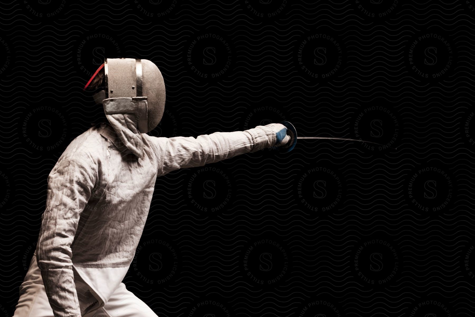 A person wearing a fencing mask and protective gear is lunging forward with a sword