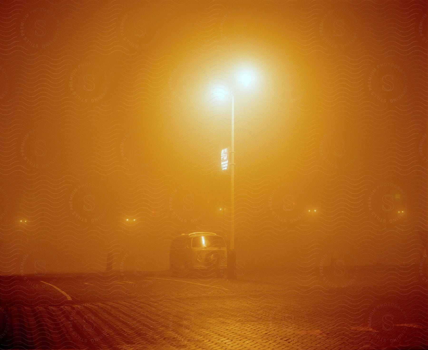 A van parked under orange street lights on a hazy night