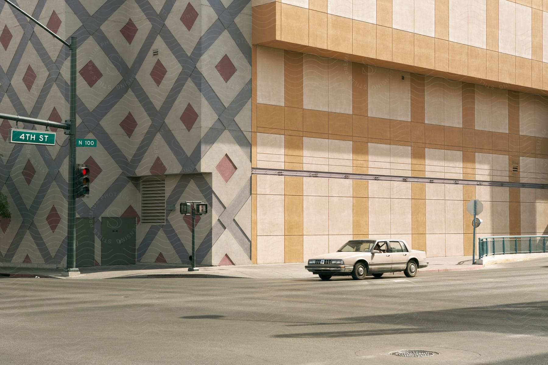 An old car is stopped at a traffic light near a large building