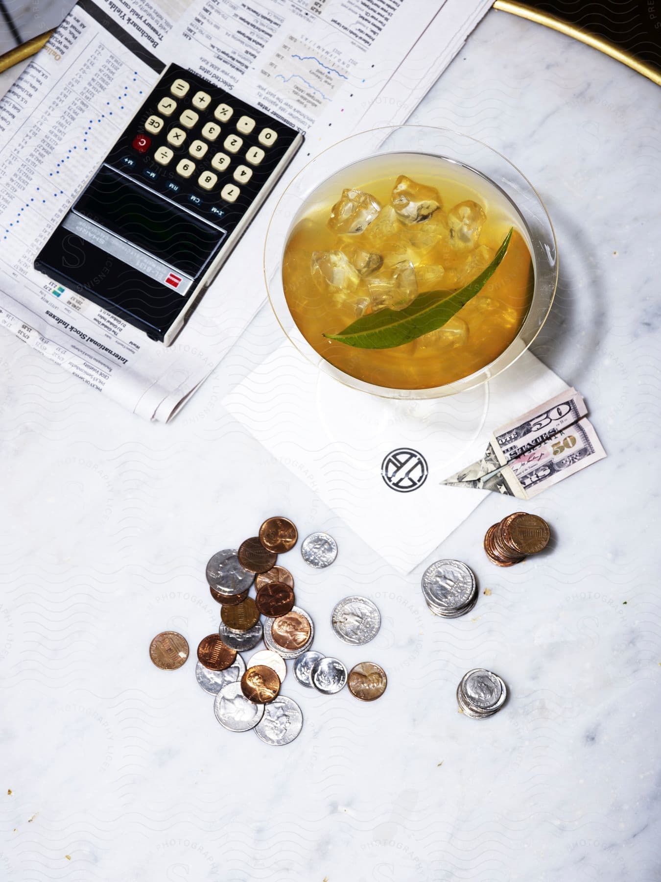 Money calculator and paper are near an alcoholic beverage on a table