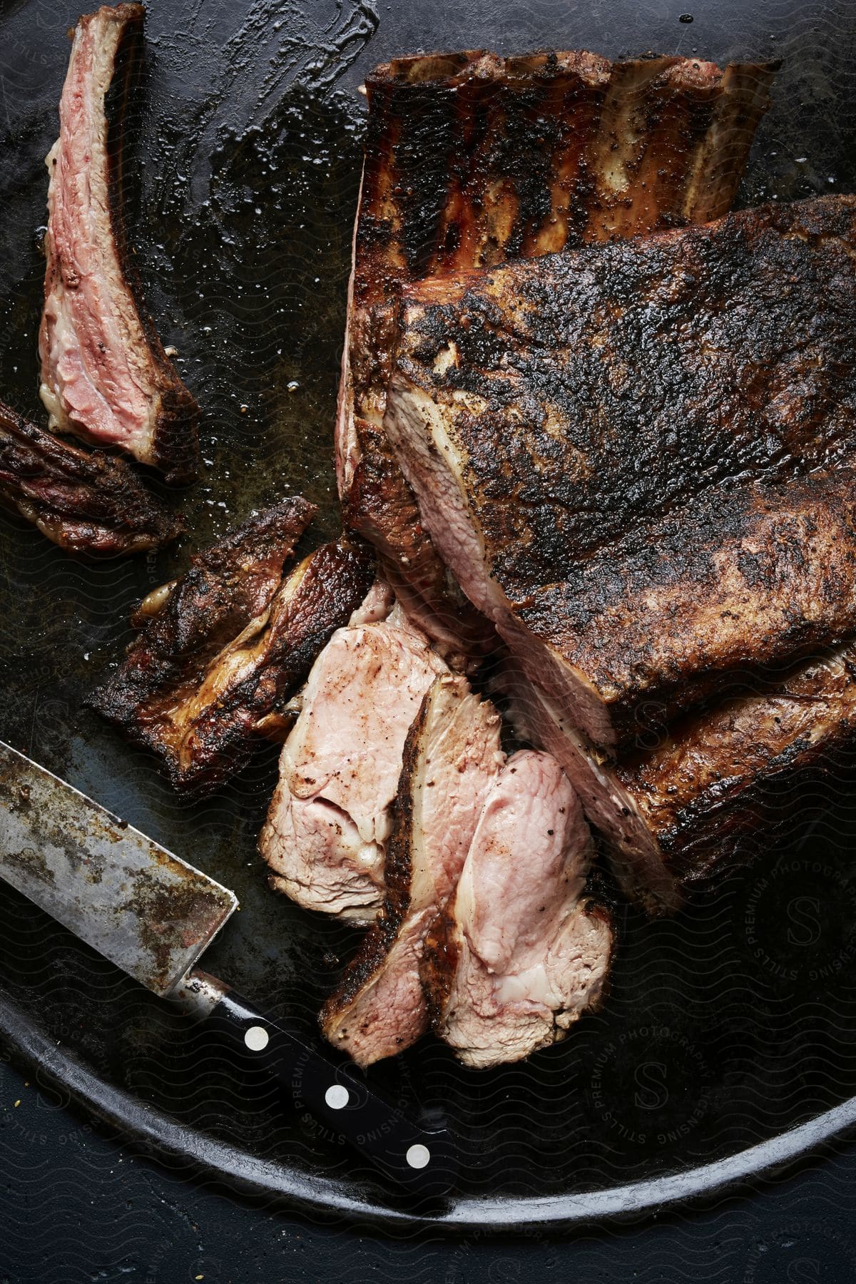 A sliced rack of bbq ribs next to a kitchen knife