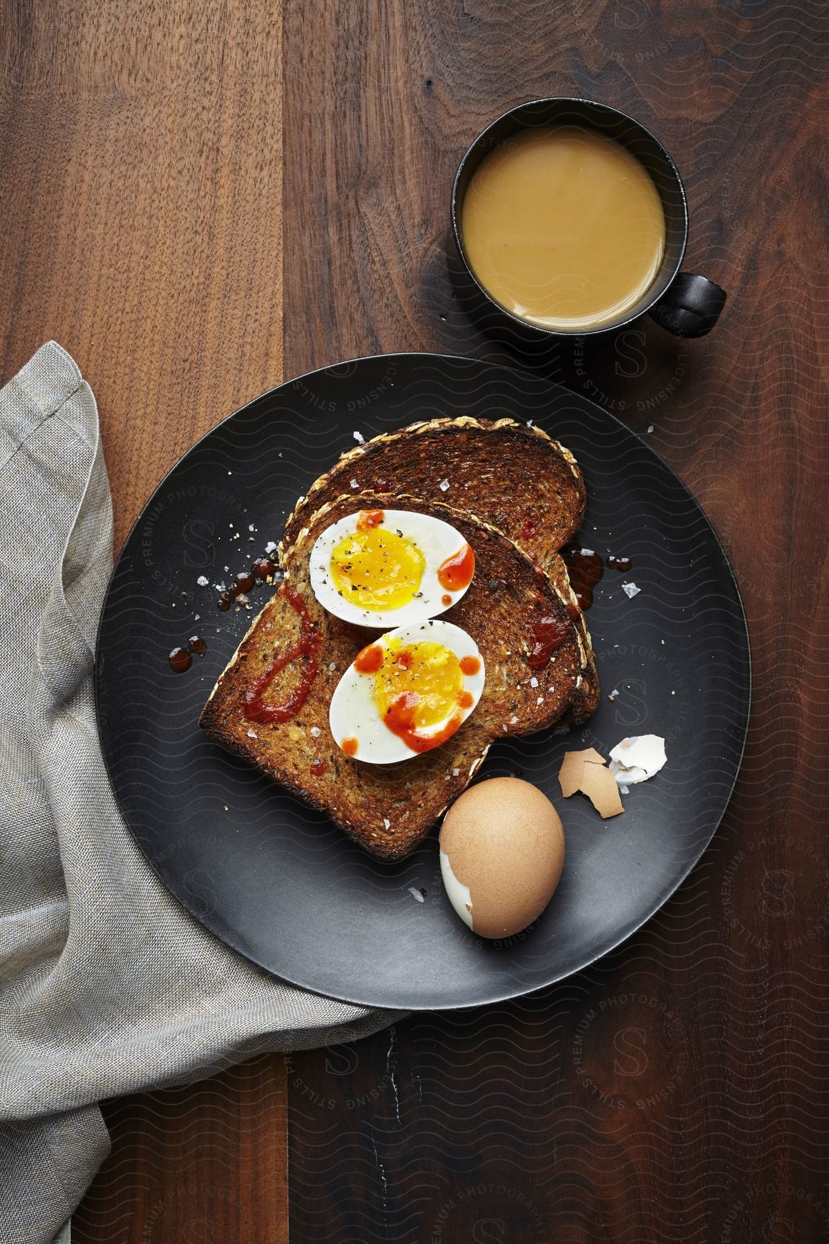 Breakfast foods including eggs and toast are on a black plate next to coffee