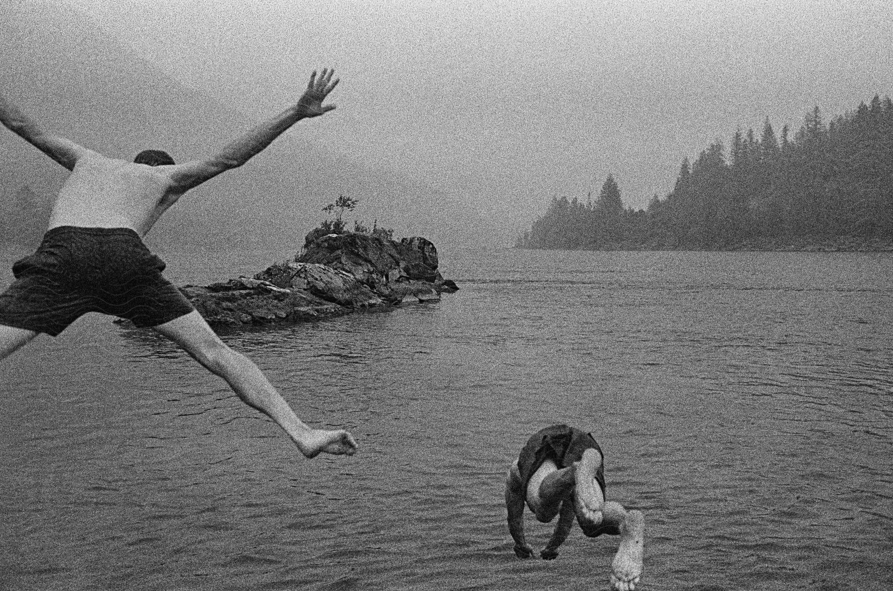 Stock photo of two men jumping and diving into a body of water