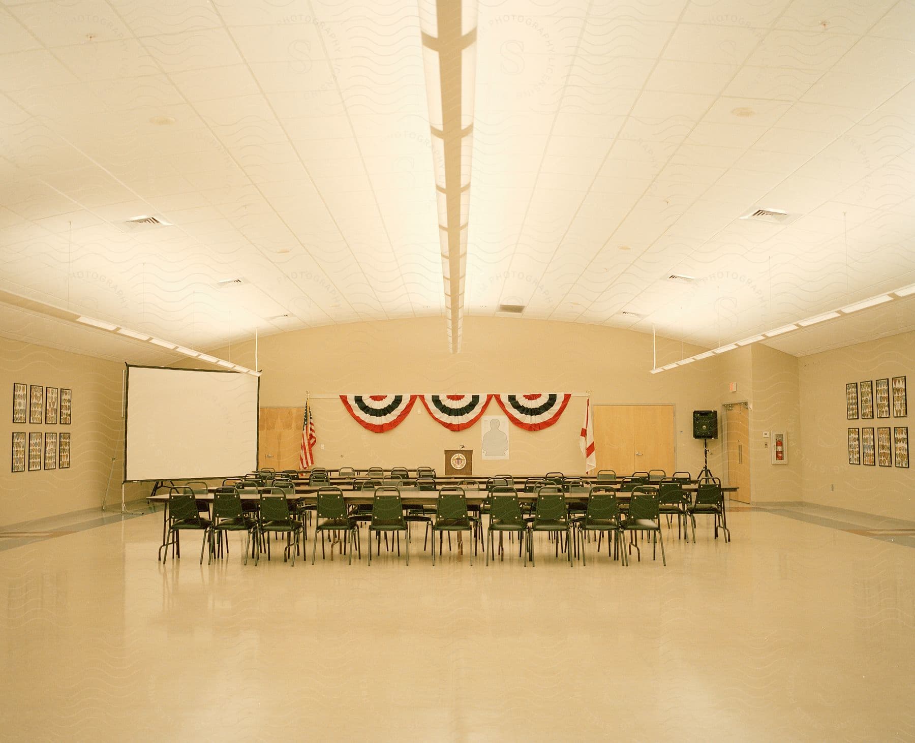 A room set up for a meeting possibly a political gathering with american flags and a blank screen