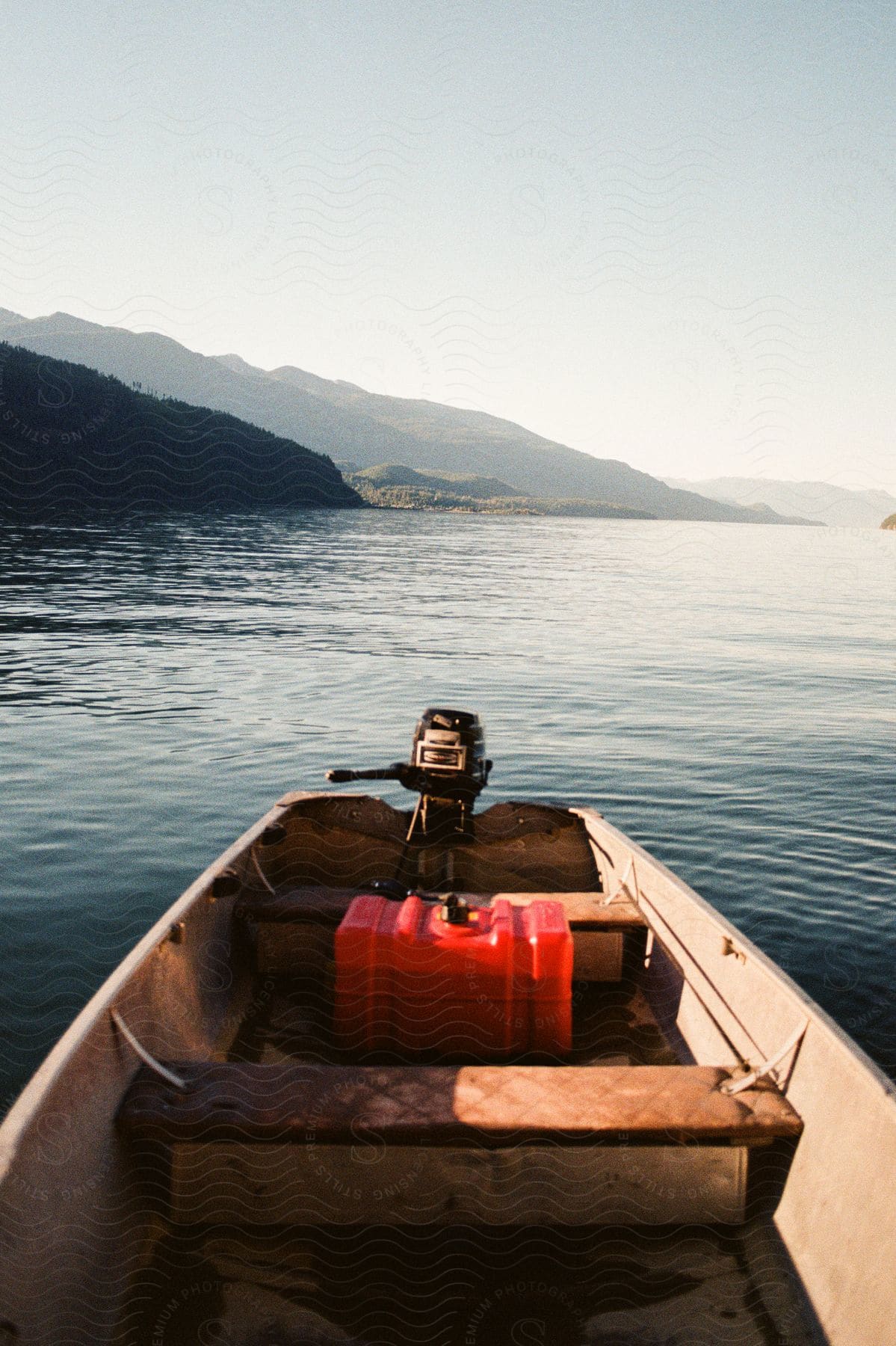 A small wooden boat sits in a lake below a mountain