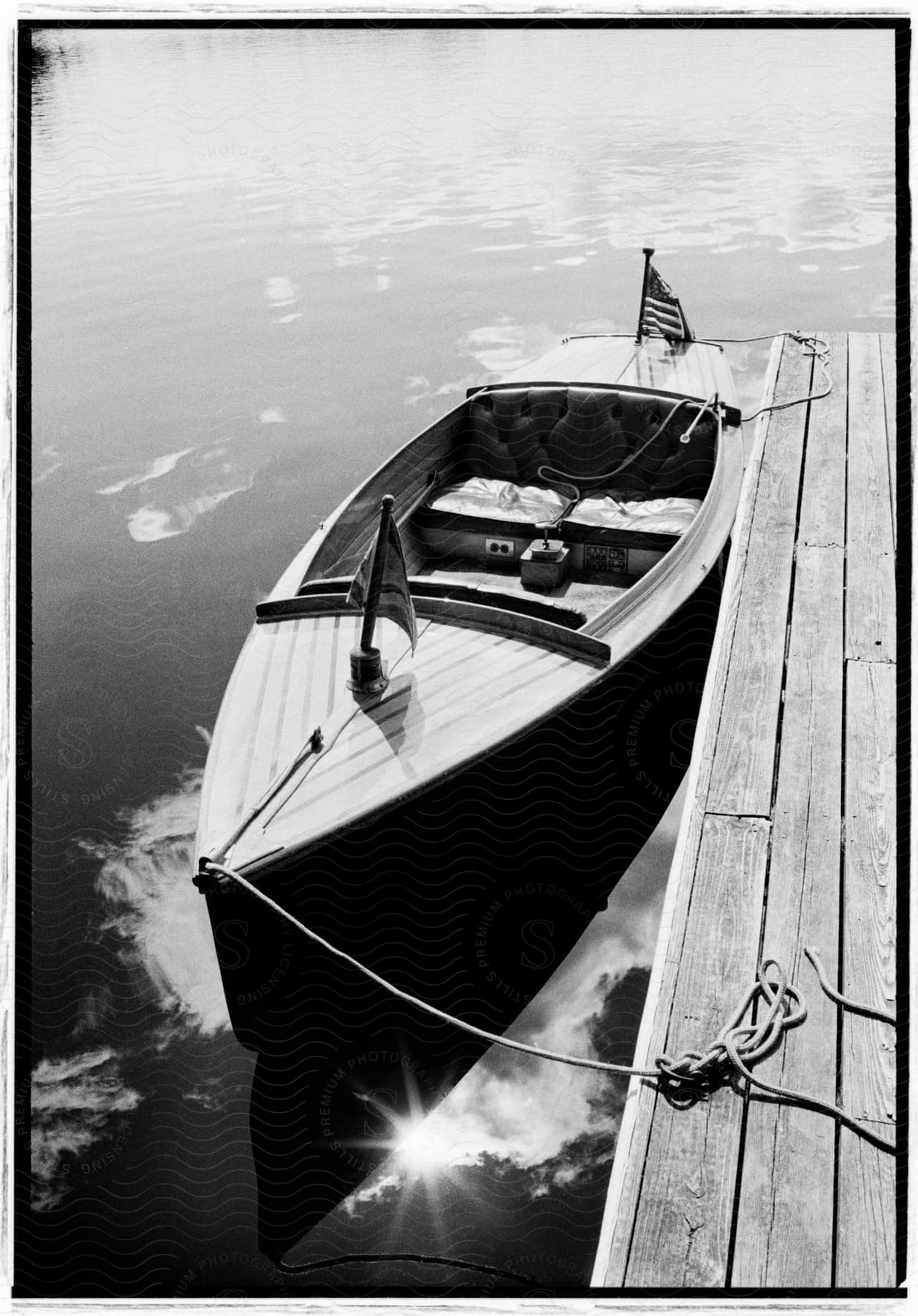 A black and white image of a canoe parked by a wooden stand inside the river