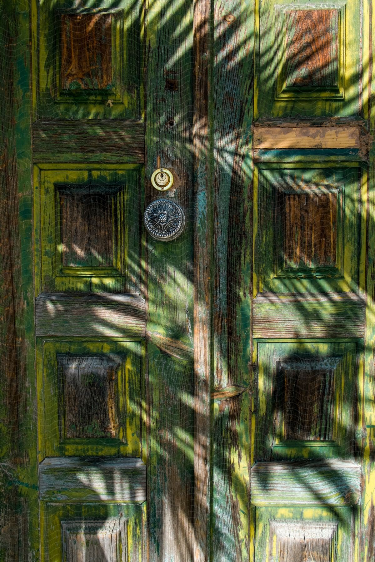 A Wooden Door With Green And Yellow Paint And An Engraved Metal Door Knob