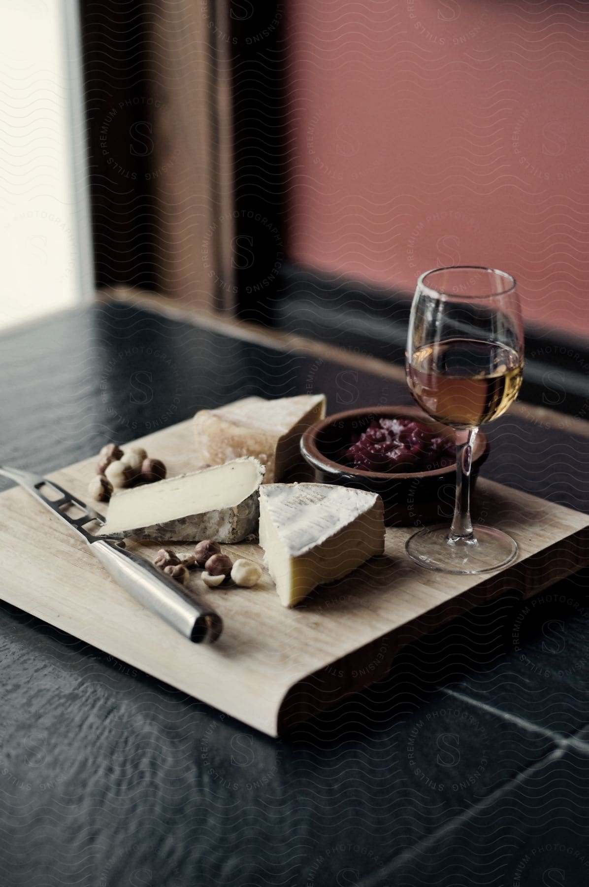 Cheeses served with white wine on a wooden tray over a table